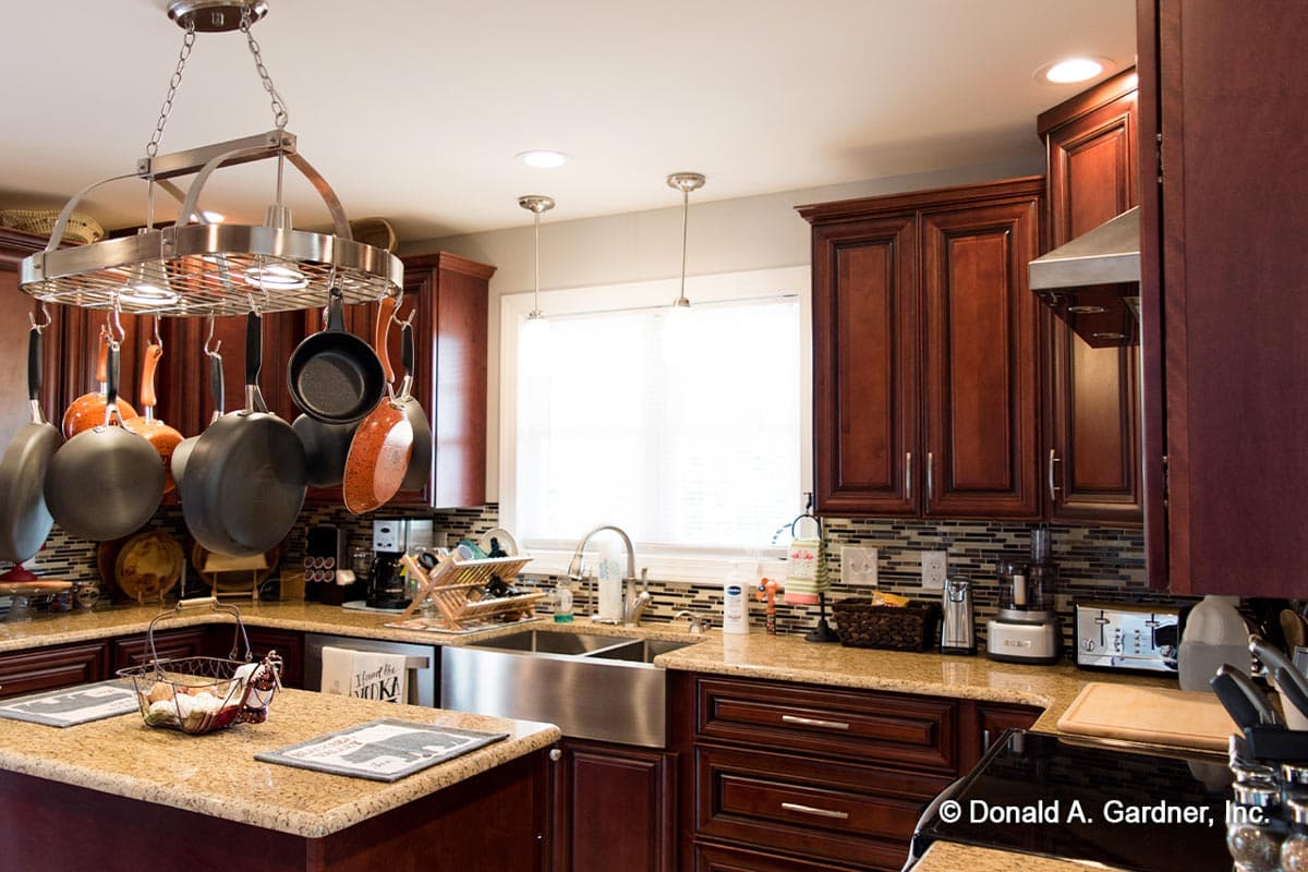 Kitchen with cherry cabinets, granite countertops, stainless steel apron sink, and pot rack.