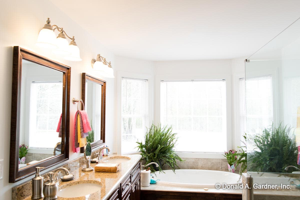 Bathroom with double vanity, granite countertop, soaking tub, and large bay windows.