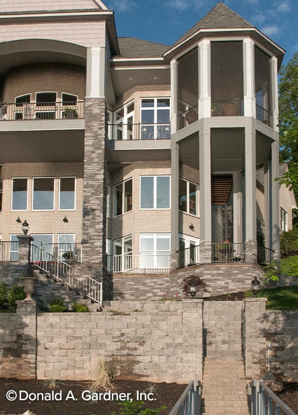 House plan exterior with multiple balconies, bay windows, a screened-in octagonal porch, and stone accents.