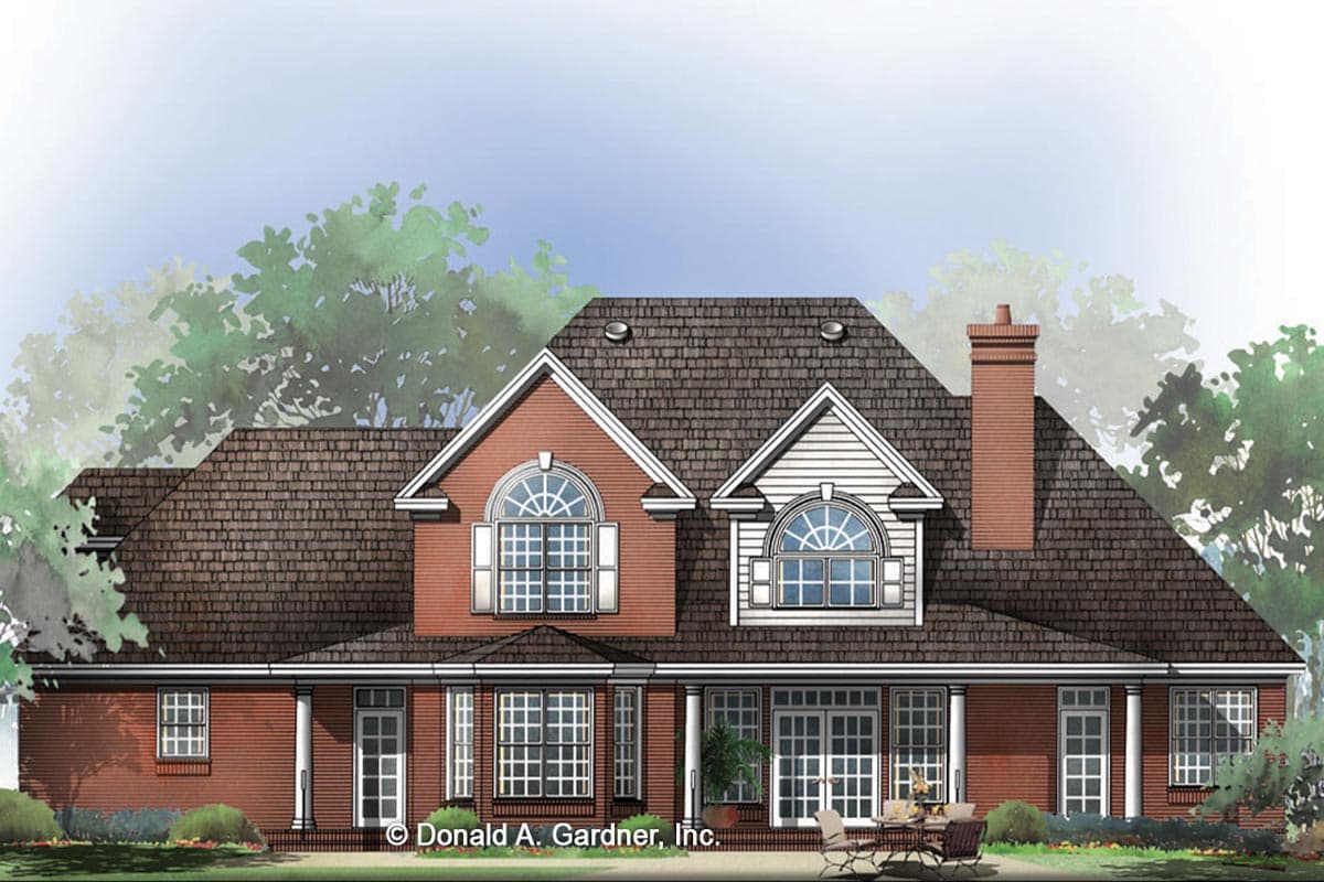 House plan exterior: Two-story brick home with wraparound porch, dual gables with arched windows, and a prominent chimney.