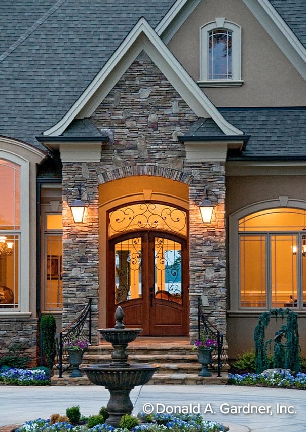 House plan exterior featuring stone facade, arched double doors with decorative grilles, stepped entrance, and gas lanterns.