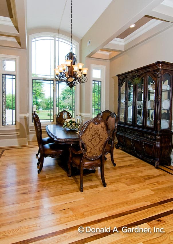 Dining room with tall arched window, ornate chandelier, traditional dining set, and china cabinet.