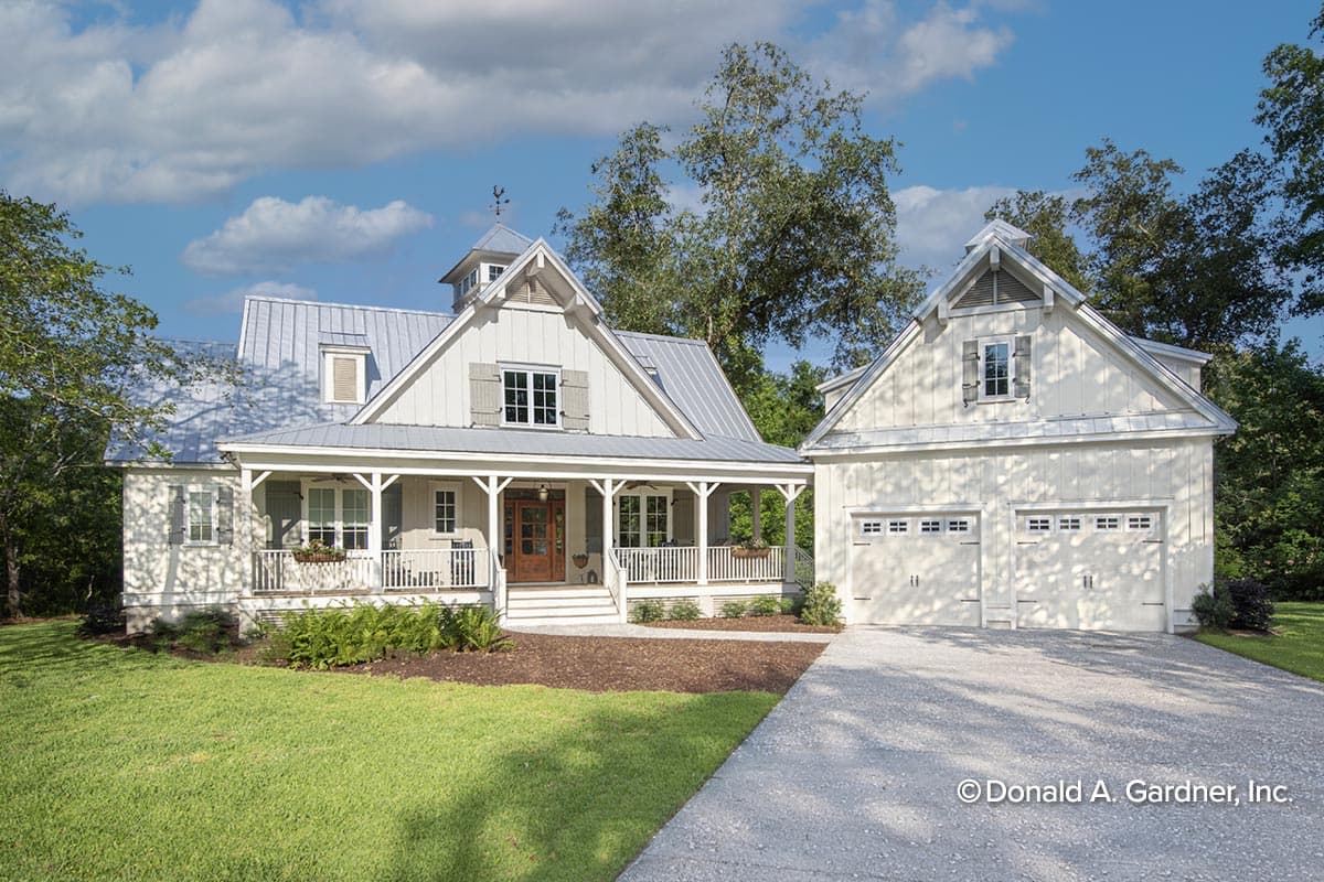 House plan exterior. Two-story farmhouse with a wraparound porch, gabled rooflines, and detached garage. Features dormers, and wood siding.