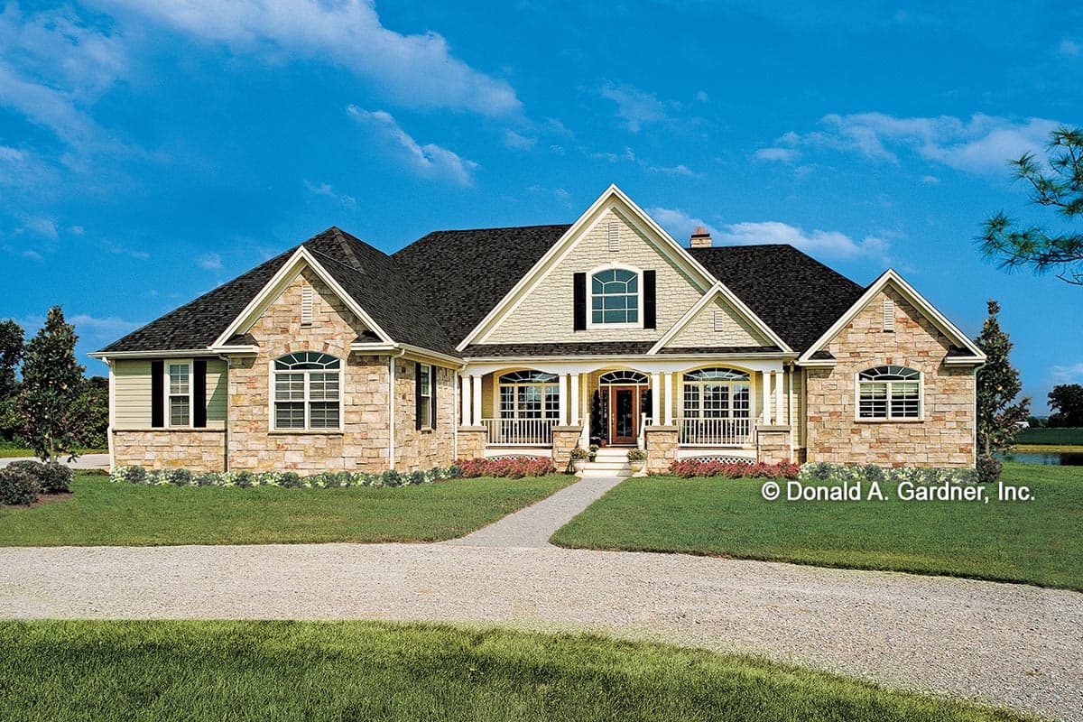 House plan exterior. Two-story with stone facade, front porch with columns, gabled rooflines, and arched windows.