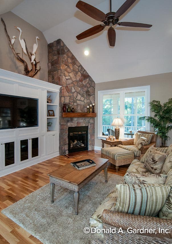 Great room with stone fireplace, vaulted ceiling, built-in entertainment center, and natural light from windows.