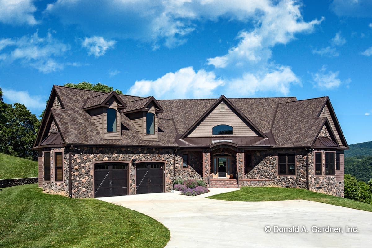 House plan exterior. Stone-clad home with multiple gables, dormers, and a covered entry. Features a two-car garage.