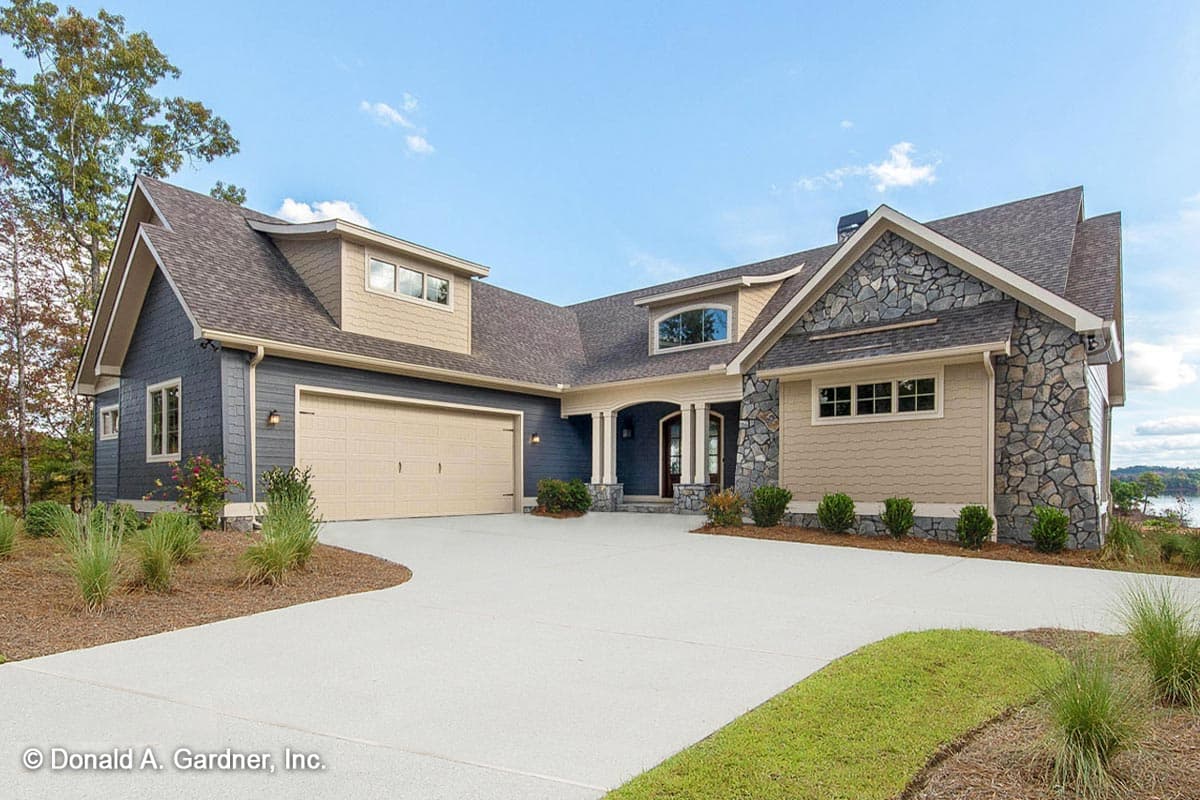 House plan exterior. Two-story with a stone facade, gable roof, and attached garage. Features include a covered entry and dormers.