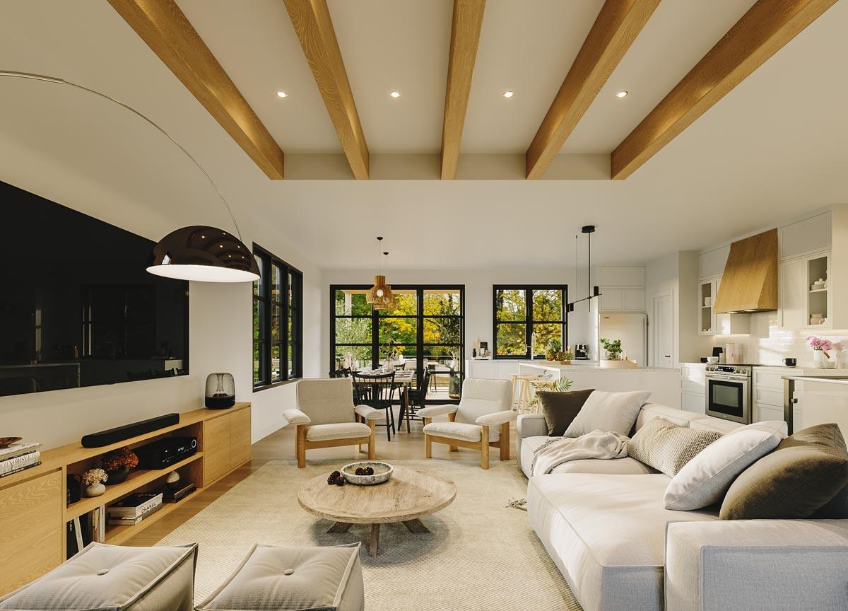Open-concept living area with a vaulted ceiling featuring exposed wood beams, a sectional sofa, and an adjacent dining area and kitchen.
