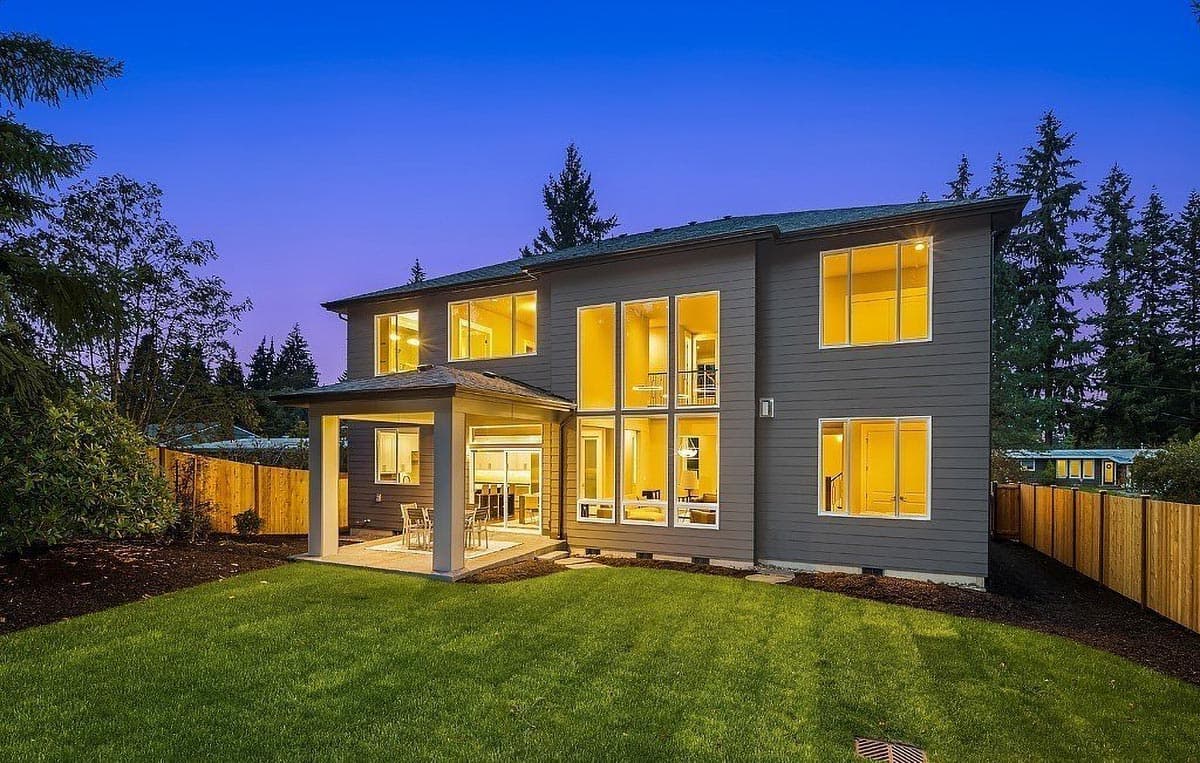 Modern two-story house plan exterior with covered patio, expansive windows, and dark gray siding.