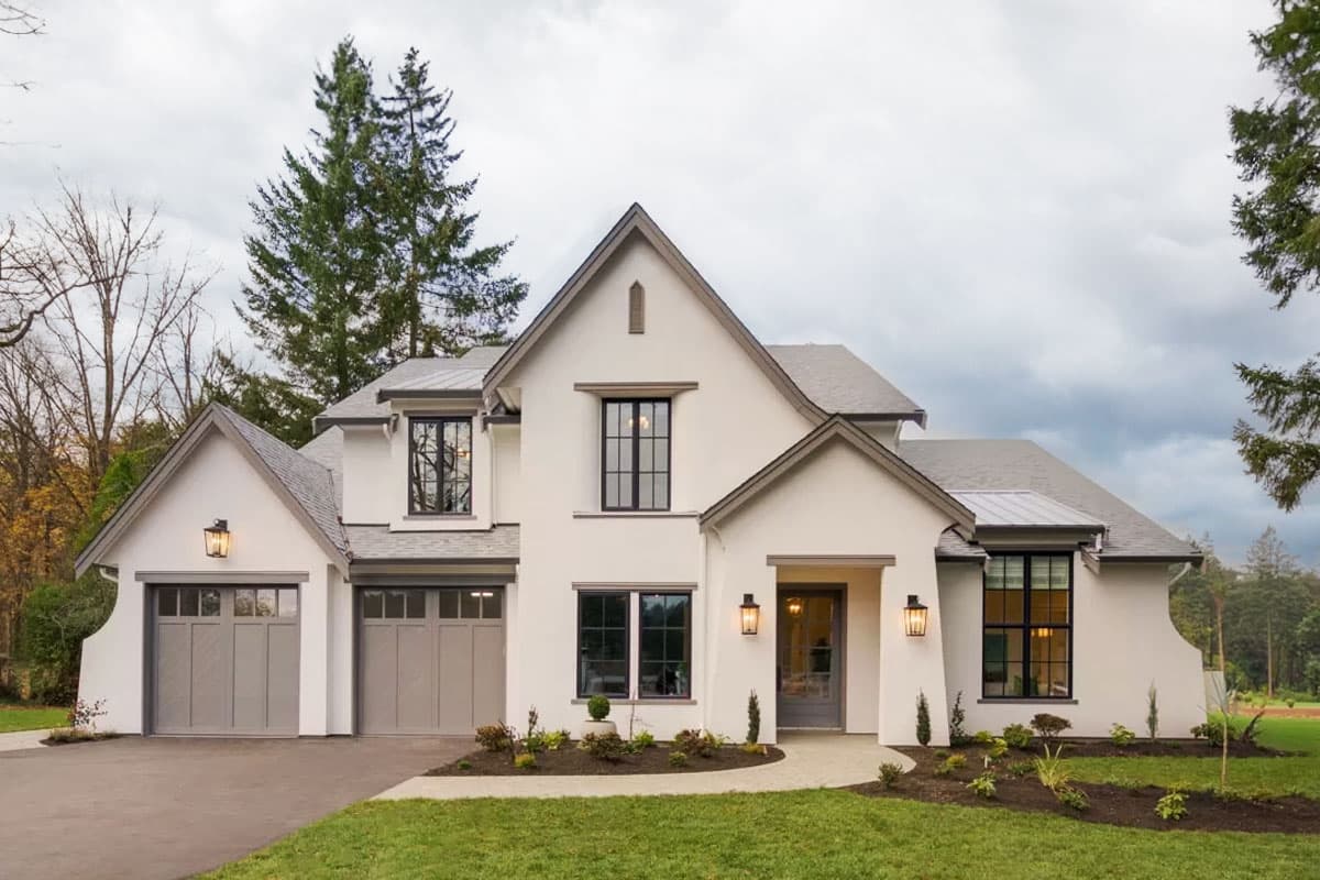 House plan exterior: Two-story modern farmhouse with stucco finish, gabled rooflines, dormers, and a side-entry two-car garage.