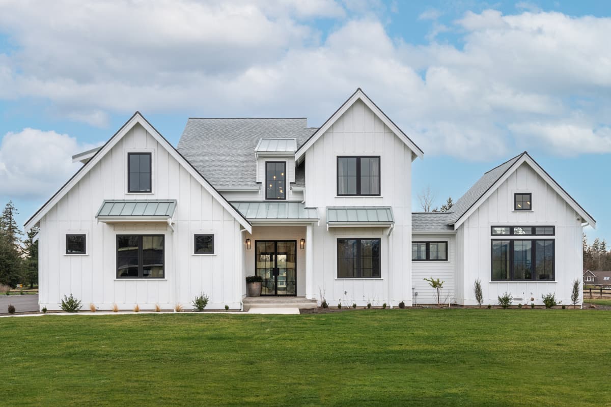 House plan exterior. Modern Farmhouse style, two stories. Features include multiple gables, metal awnings over windows, and a covered entry porch.