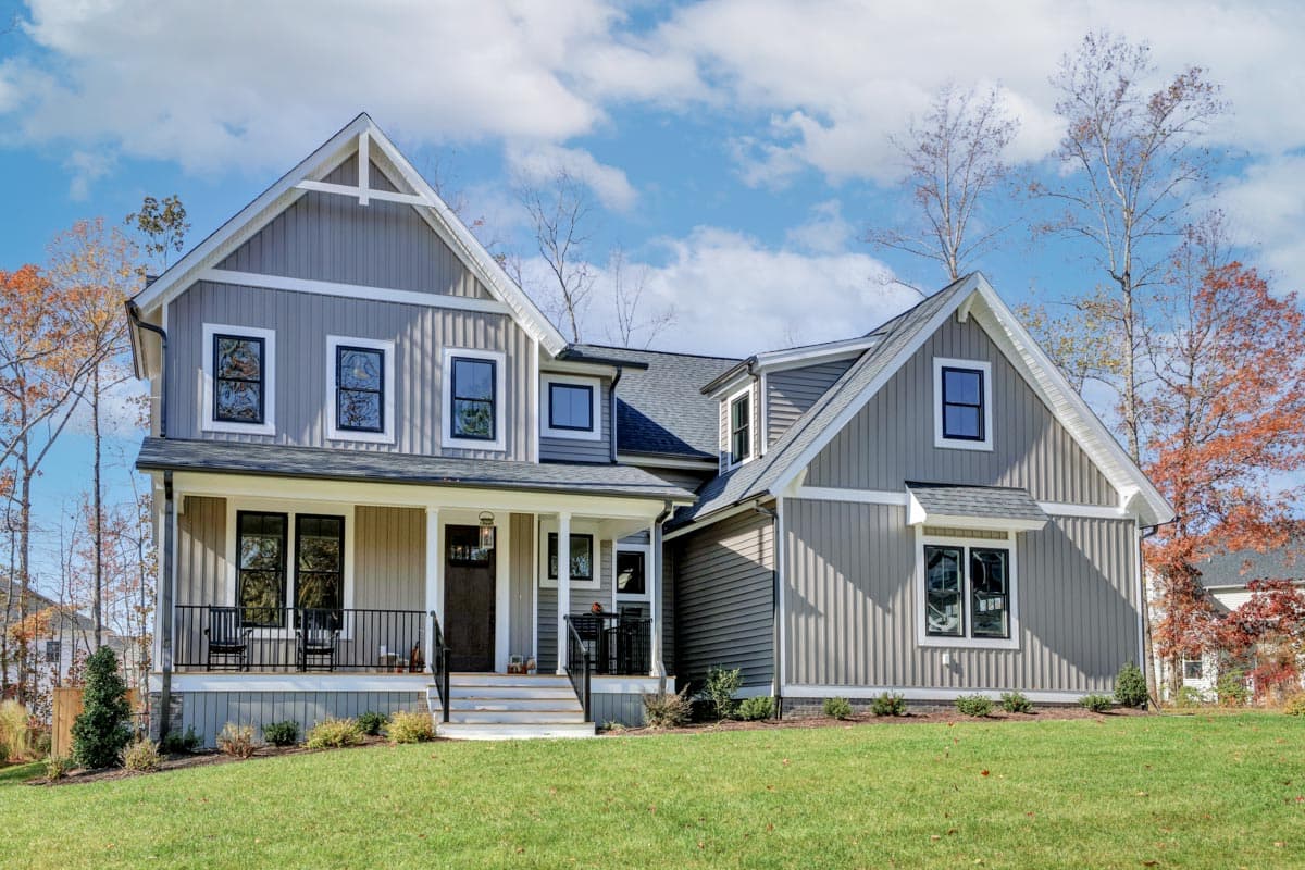 House plan exterior featuring a two-story farmhouse style, with a front porch, multiple gables, and vertical siding.