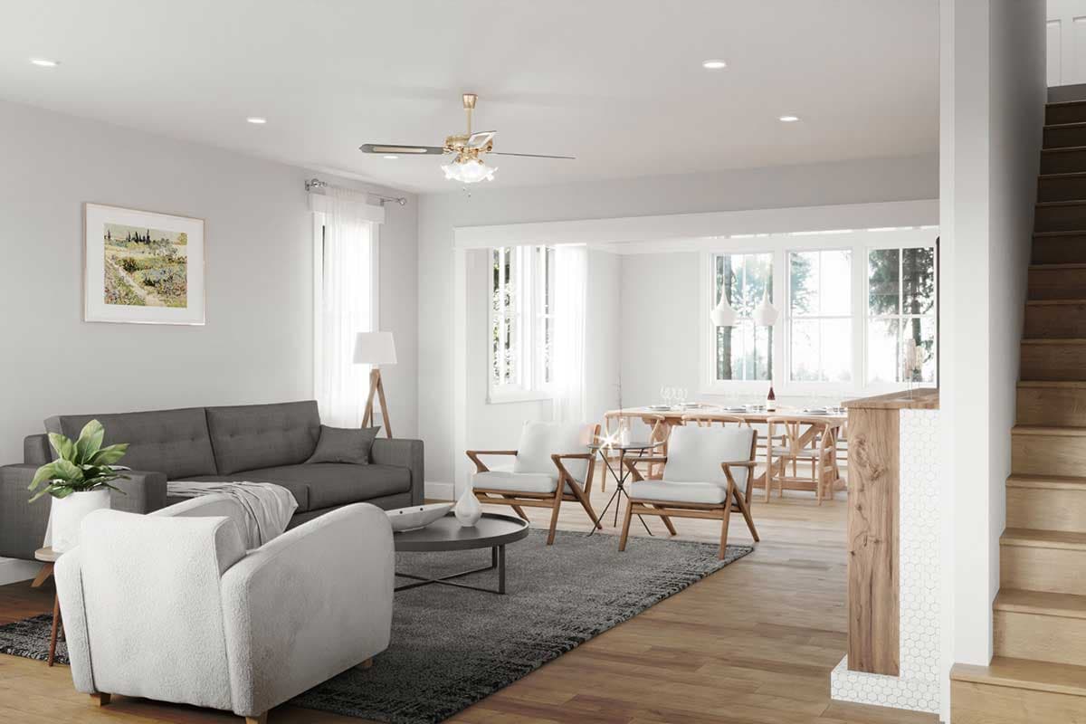 Living and dining area with gray sofa, white armchairs, wood dining table, and staircase.