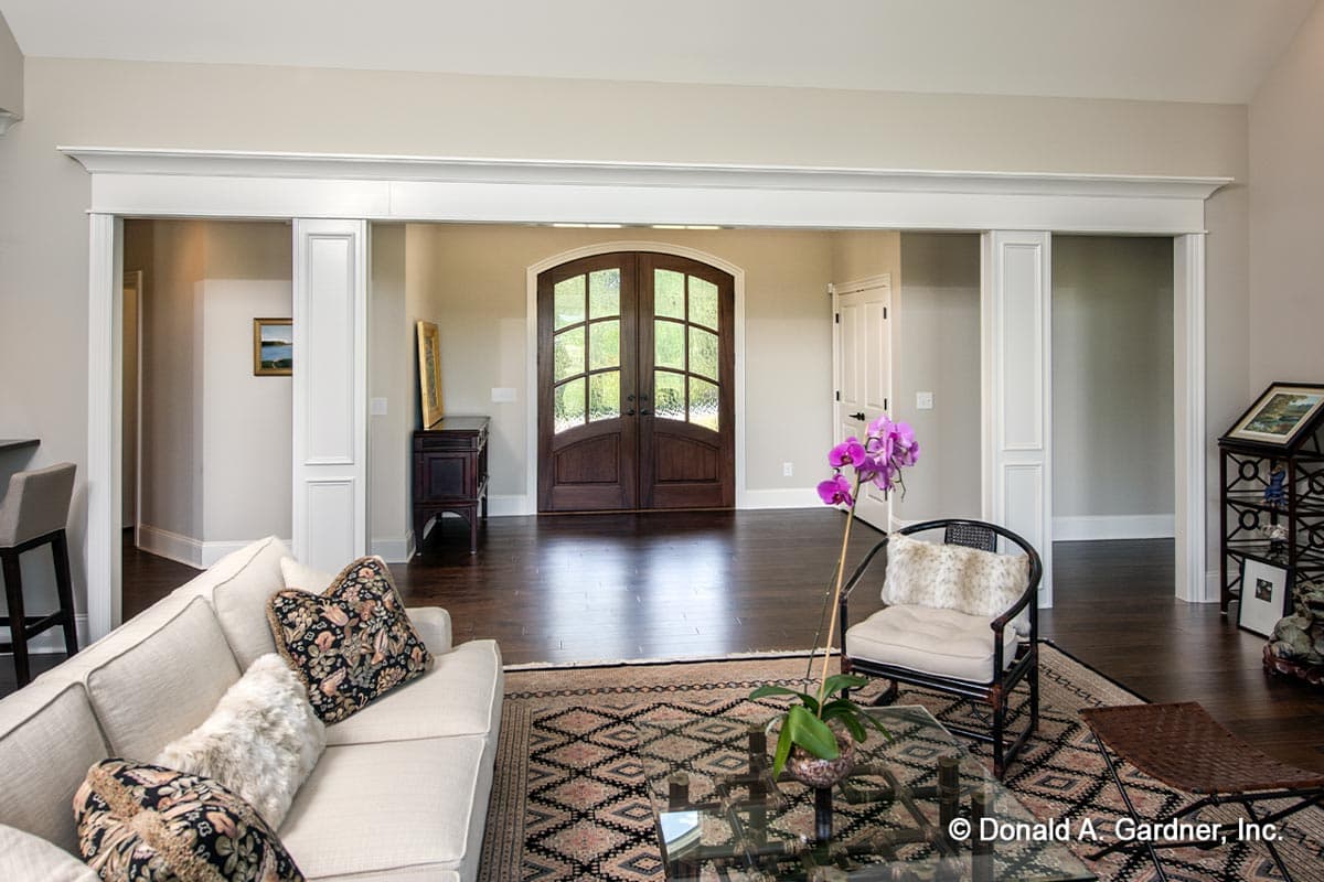 Interior view of living room looking toward arched double front doors with mullions and a single door to the right.