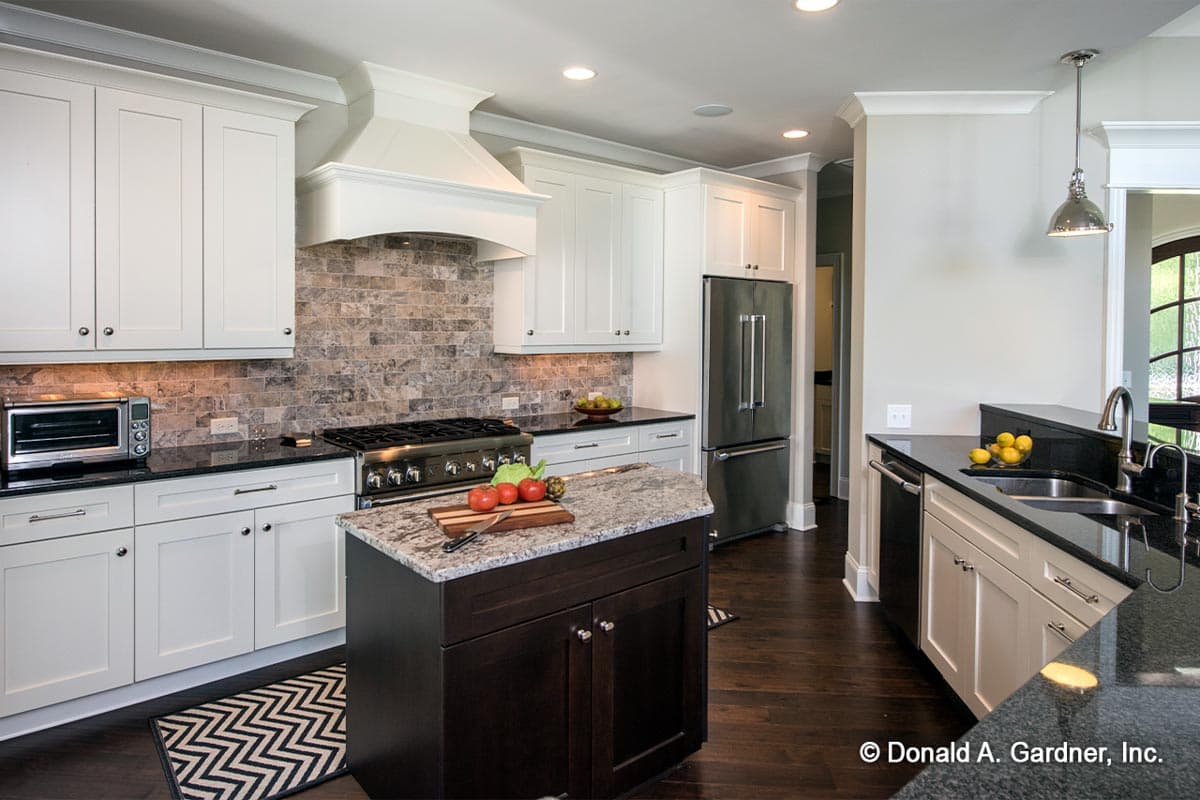 Kitchen with white cabinets, stone backsplash, large island with dark wood base, and stainless steel appliances.