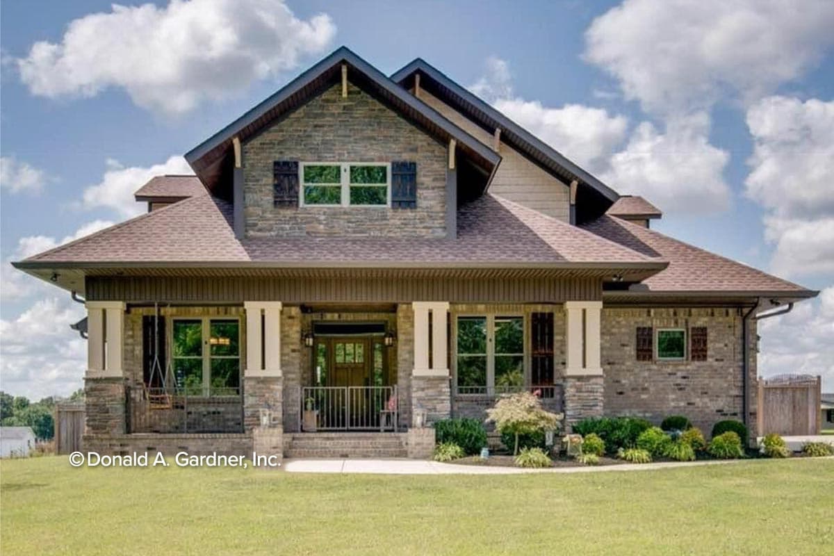 House plan exterior. Two-story home with Craftsman style. Features include gables, a covered front porch, and stone facade.