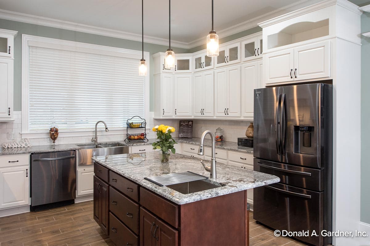 Kitchen with a central island, stainless steel appliances, white cabinets, granite countertops, and pendant lighting.