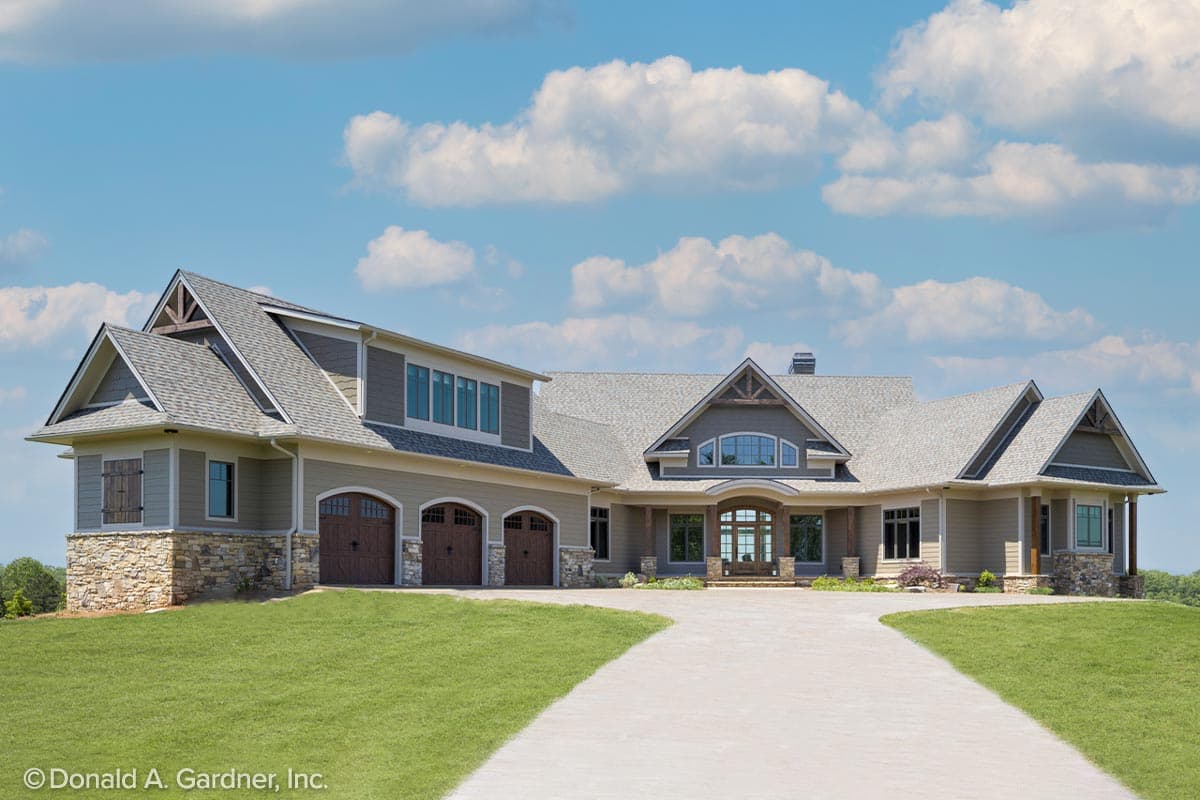 House plan exterior with Craftsman influences. Features include gables, stone accents, and a three-car garage. Two-story with covered entry.