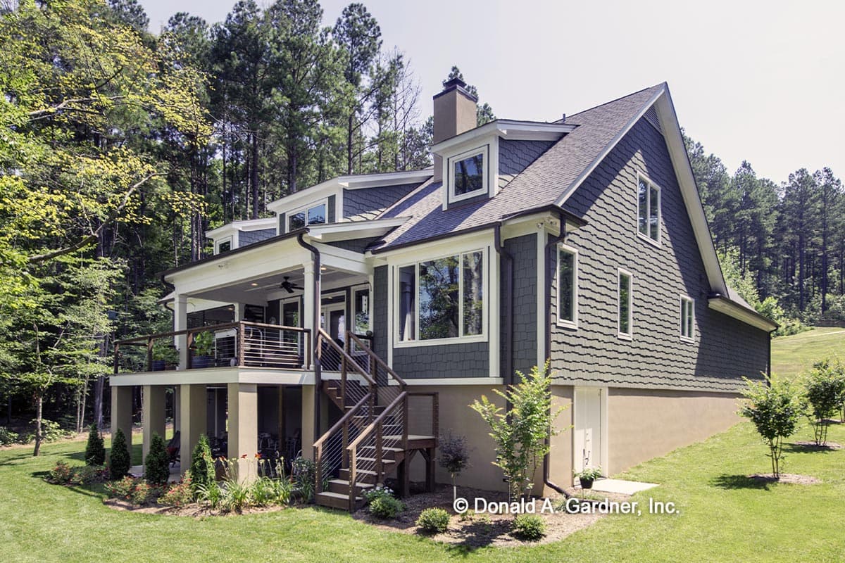 House plan exterior: two-story home with covered porch, multiple gables, dormer windows, and a sloped lot.