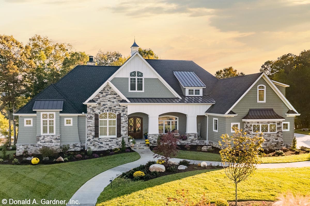 House plan exterior. Two-story home with Craftsman-style elements. Features include a front porch, multiple gables, and stone accents. Dark rooflines.
