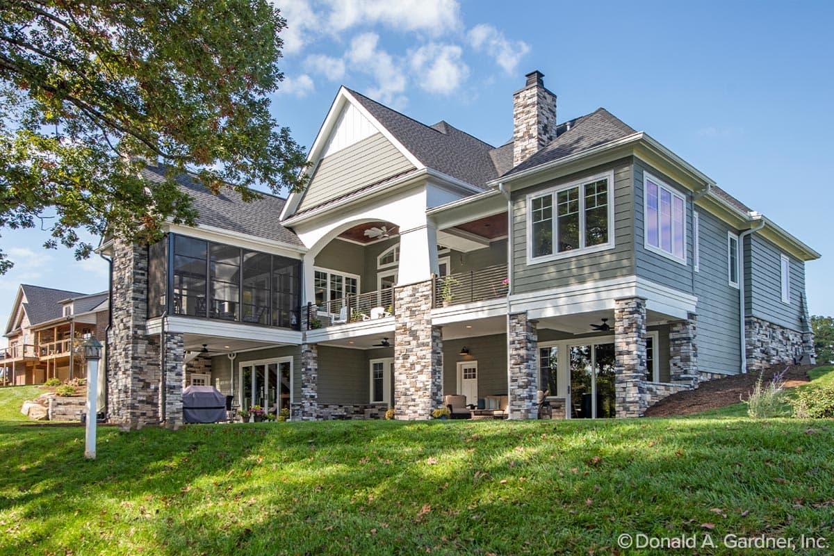 House plan exterior with stone accents, multiple covered decks, screened porch, and layered rooflines.