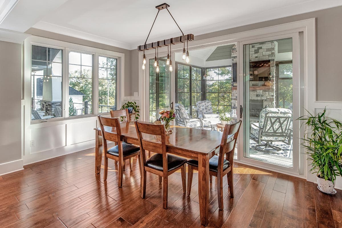 Dining room with wood table and chairs, large windows, and sliding glass doors to a sunroom with fireplace.