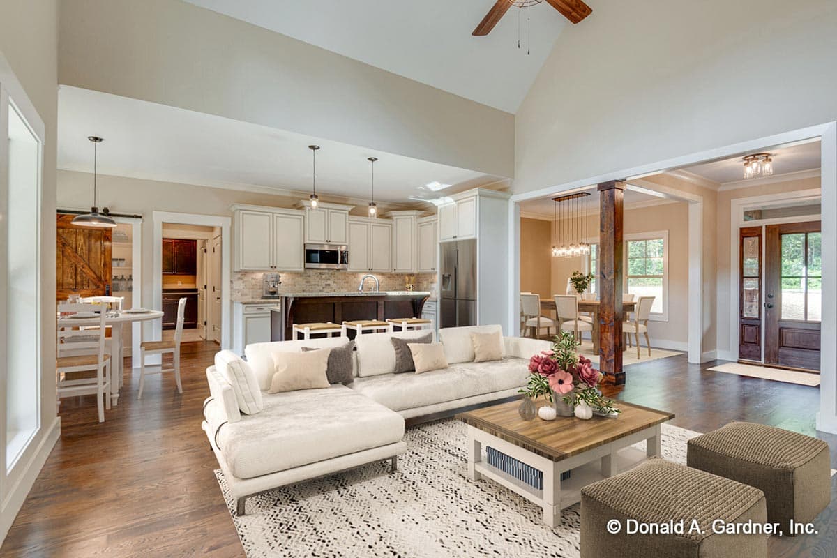 Open concept living area with vaulted ceiling, kitchen island, dining room, and entryway.