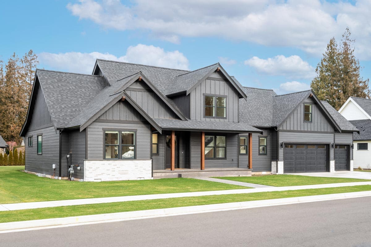 House plan exterior. Two-story, Modern Farmhouse style with gabled roof, covered porch, and attached garage. Exterior features dark siding.