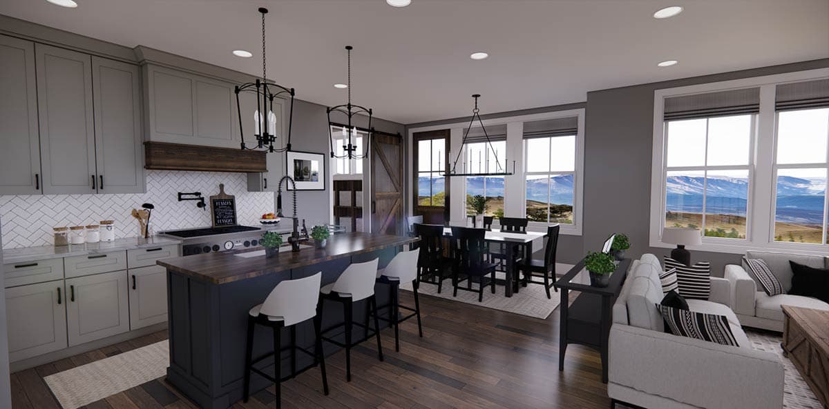 A modern kitchen and dining area featuring an island with bar stools, dark table and chairs, and a living room with mountain views.