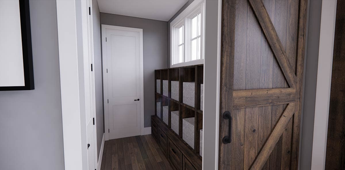 Hallway with a wooden barn door on the right, storage cubbies with baskets, and a white door with black hardware.