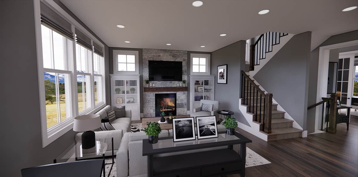 Cozy living room with a stone fireplace, large windows, a staircase, and modern furniture; a bright and airy atmosphere.