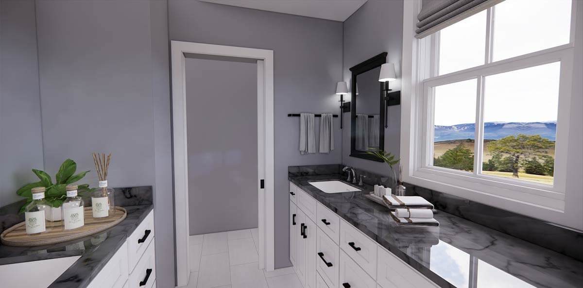 A modern bathroom features white cabinetry, a dark countertop, and a window with a mountain view. A large mirror and candles are present.