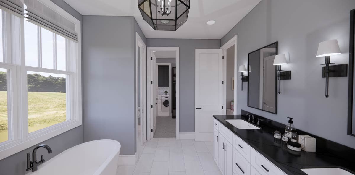 Modern bathroom with white cabinetry, black countertop, and large mirror. Includes a bathtub near a window offering a view of a grassy field.