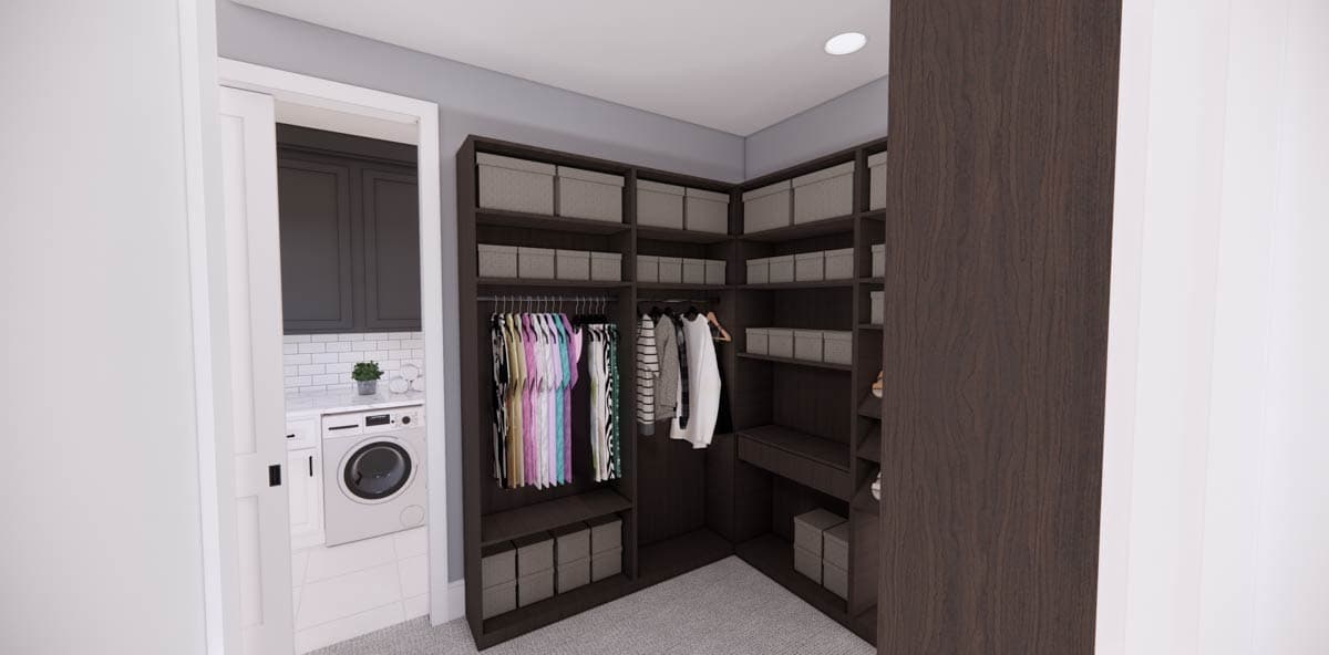 A walk-in closet with dark wood shelving, gray boxes, and hanging clothes. Adjacent, a glimpse of a laundry room with a washing machine is visible.