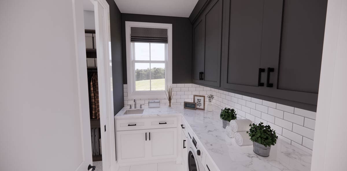 Modern laundry room with marble countertop, white cabinets, and dark gray upper cabinets. Window view of a green field in the background.