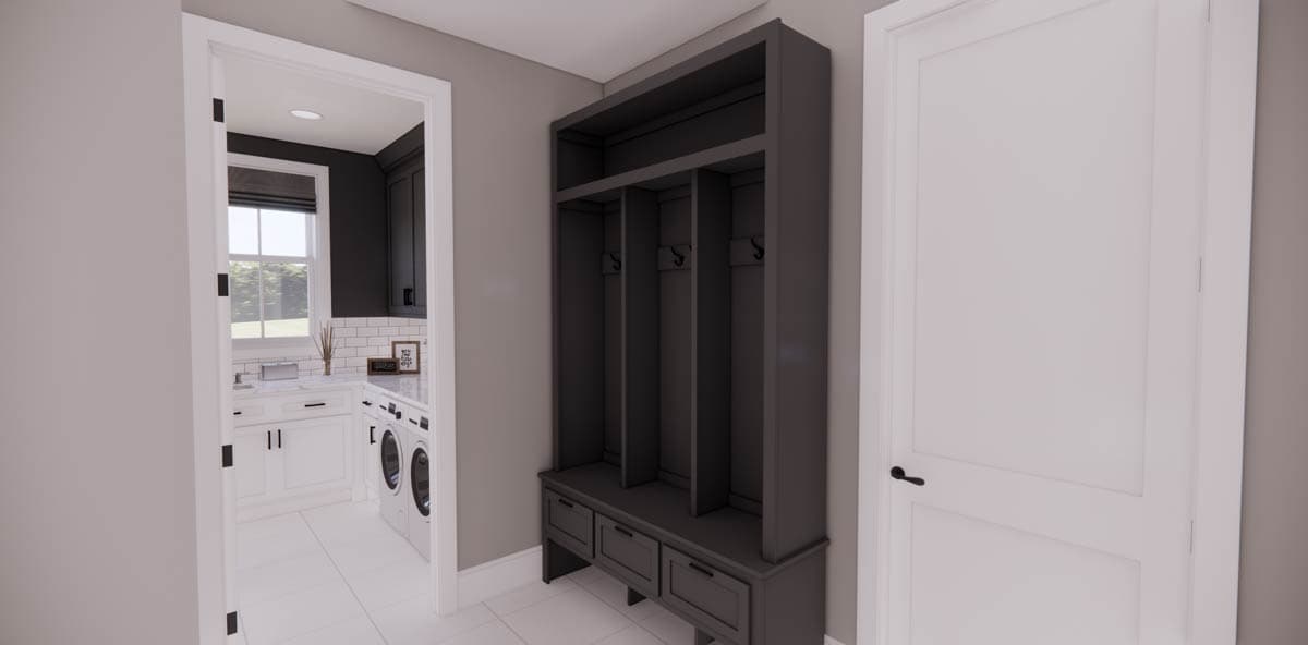 A hallway with a built-in dark gray storage unit with cubbies, hooks, and drawers. A doorway leads to a laundry room.