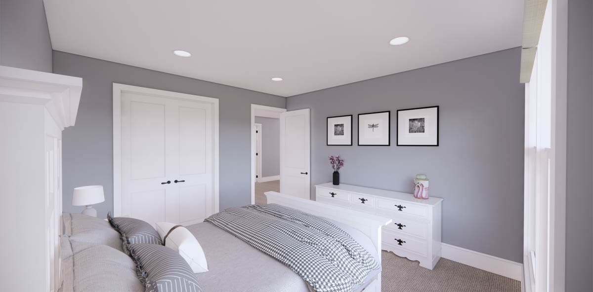 A modern bedroom features a white bed with gray bedding, a white dresser with framed art on a gray wall, and two closed doors.