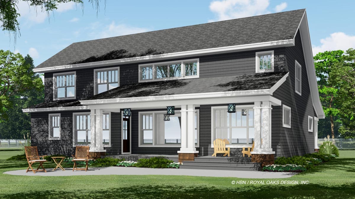 A two-story house with dark gray siding, white trim, and a porch with columns. There are Adirondack chairs on the porch and a small table on the lawn.
