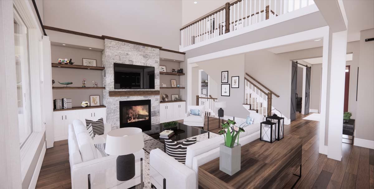 A modern living room with a stone fireplace, white sofas, and a second-story balcony overlooking the space. Natural light floods the room.