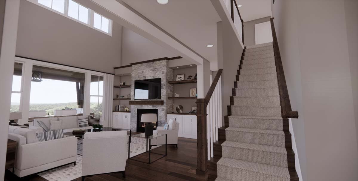 Spacious, modern living room with a stone fireplace, built-in shelves, and a staircase leading upstairs. Large windows provide a view of the outdoors.