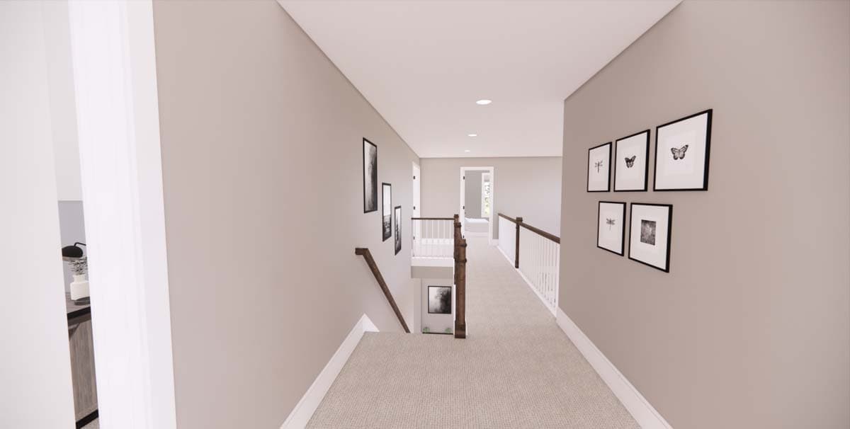 A hallway with neutral-toned walls, a light beige carpet, and a staircase. Several framed pictures are mounted on the wall.