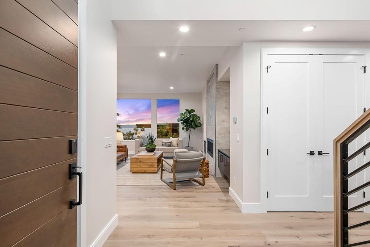 Interior view showing entry with a wood door, double interior doors, and a living area with fireplace and large windows.