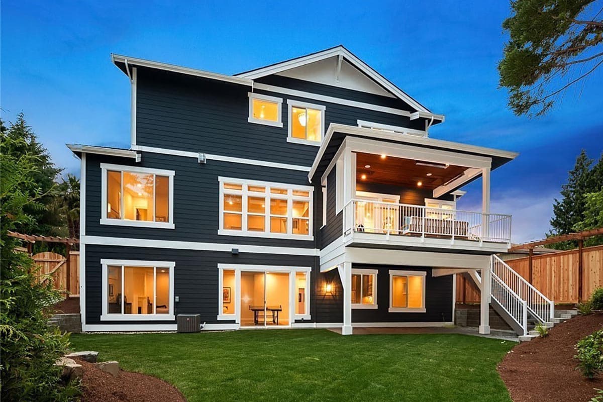 Two-story Modern Farmhouse exterior with dark siding, white trim, large windows, and a covered upper deck with railing and stairs.
