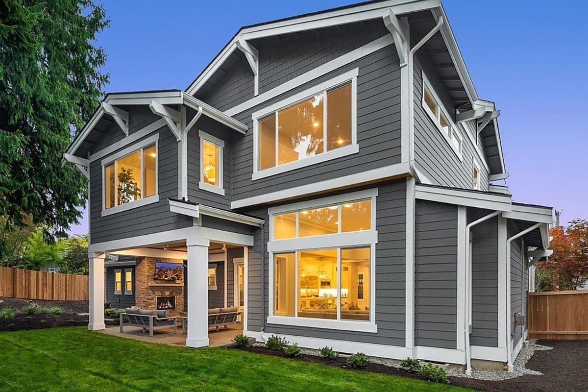 House plan exterior, two stories, with gables, wide windows, and covered patio with fireplace.