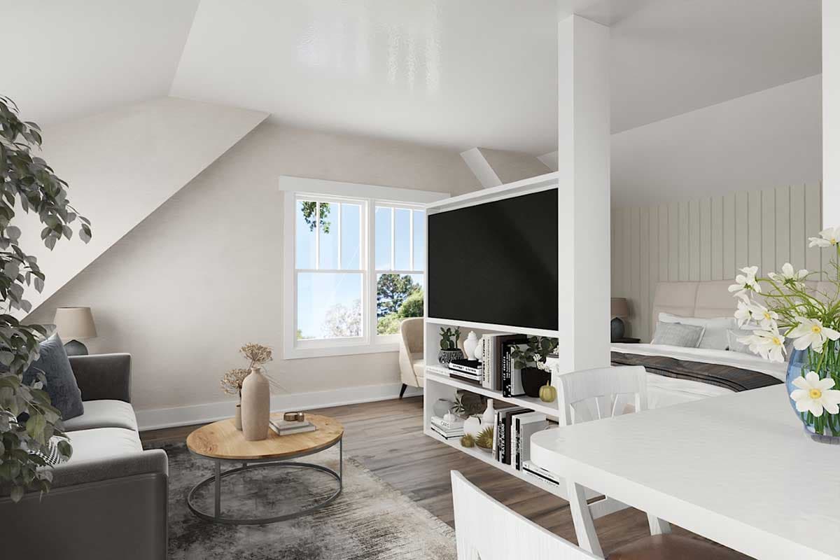 Interior view of a studio apartment with living area, dining table, and bedroom separated by a media console.