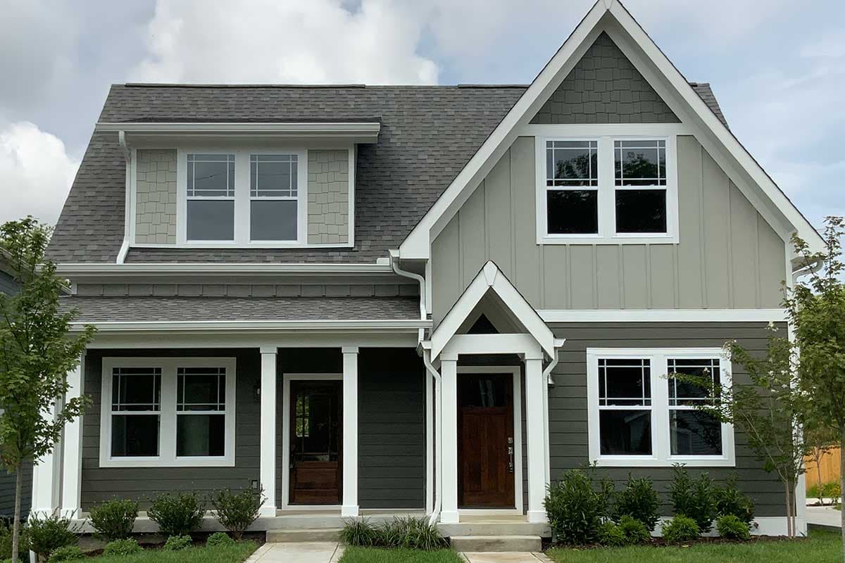 House plan exterior featuring Craftsman style, two stories, and multiple gables. It has a front porch with columns and a contrasting roofline.