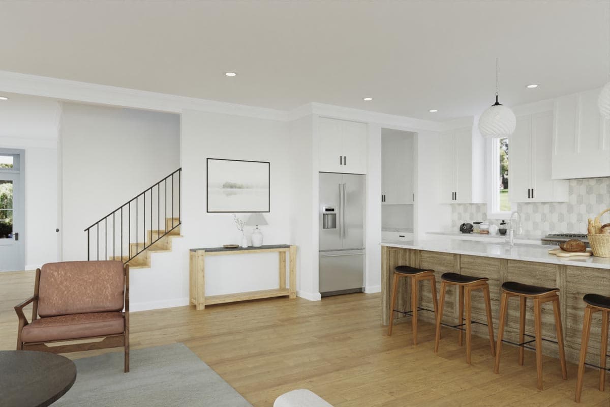 Modern open concept living area with a kitchen island, stainless steel refrigerator, and stairs leading to the second floor.