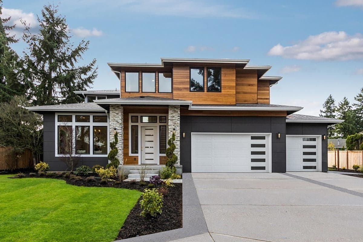 House plan exterior. Modern style, two-story home with flat rooflines, wood accents, and a front-facing garage. Stone-clad entry pillars.