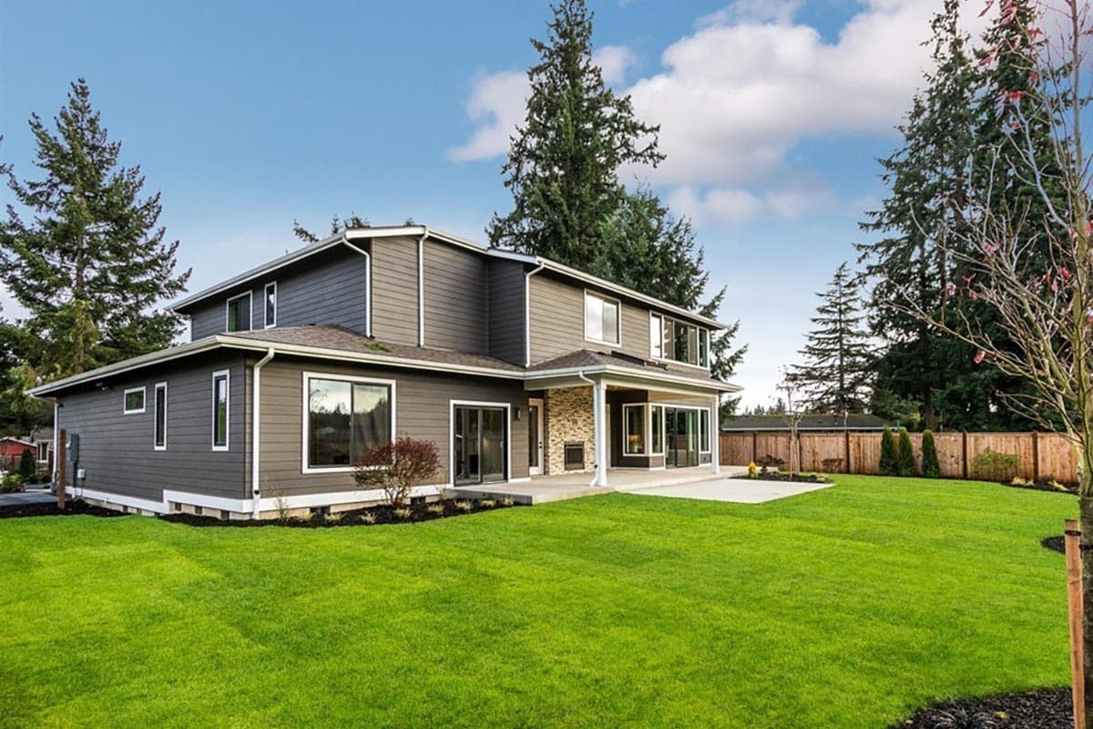 House plan exterior: Two-story contemporary home with horizontal siding, multiple gables, and a covered patio with stone accents.