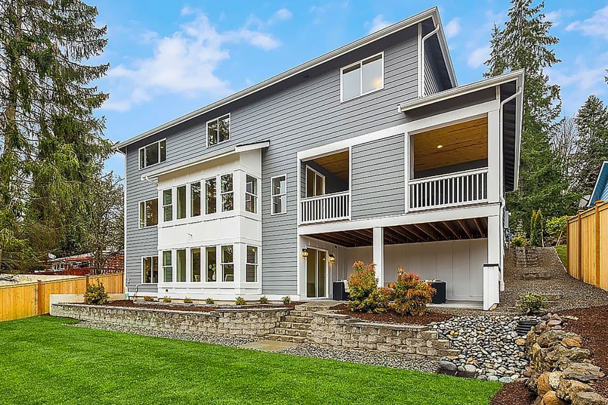 House plan exterior of a multi-story modern home with a bay window, two covered balconies, and sloped rooflines.